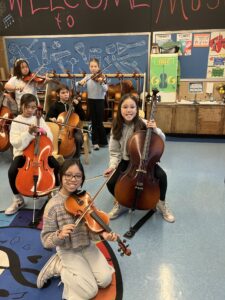 Six students get ready to play their string instruments in music class